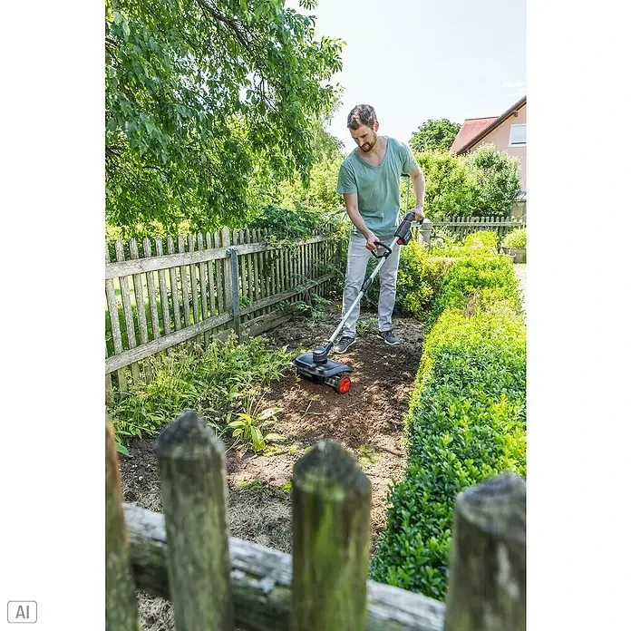 AL-KO 18V/36V Akku-Rasenlüfter ARD 1835 - Anzahl Akkus: 1 Akku, 2,5 Ah, Arbeitsbreite: 35 cm - Ein Mann benutzt eine Kärcher Akku-Gartenfräse in seinem Garten, um den Boden zu bearbeiten. Das Gerät hat rote Räder und ist einfach zu bedienen.