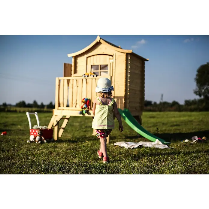 Timbela Spielhaus - L x B x H: 112 x 146 x 212 cm, Holz, Natur - Kind vor dem hölzernen Spielhaus mit Rutsche.
