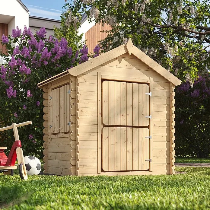 Timbela Spielhaus M516 - L x B x H: 112 x 146 x 145 cm, Holz, Natur - Ein hölzernes Spielhaus im Garten mit einem roten Dreirad und einem Fußball im Gras.