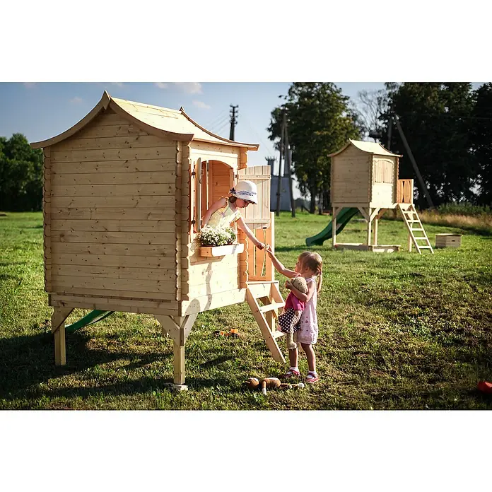 Timbela Spielhaus - L x B x H: 112 x 146 x 212 cm, Holz, Natur - Ein Kinderhaus aus Holz mit zwei kleinen Mädchen beim Spielen im Garten, mit einem zweiten Spielhaus im Hintergrund.