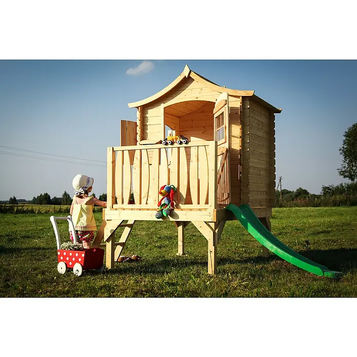 Timbela Spielhaus - L x B x H: 112 x 146 x 212 cm, Holz, Natur - Kinderspielhaus aus Holz mit Rutsche, ein toller Spielplatz für den Garten, während ein kleines Mädchen mit einem Spielzeugwagen davor steht.