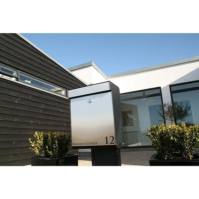 Allux Briefkasten Grundform - L x B x H: 180 x 345 x 440 mm, Schwarz / Silber, Stahl - Ein moderner Edelstahlbriefkasten der Familie Schultz mit der Hausnummer 12 vor einem modernen Haus.