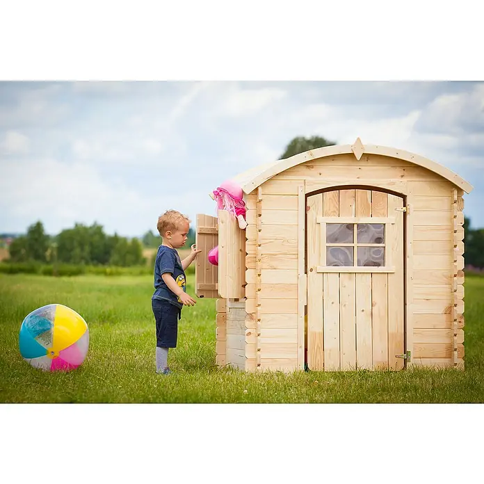 Timbela Spielhaus M505 - L x B x H: 112 x 146 x 145 cm, Holz, Natur - Junge spielt vor einem Holzspielhaus mit Puppe und Ball. Das Spielhaus ist aus hellem Holz gefertigt.