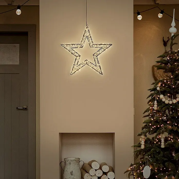 ECD Germany LED-Weihnachtsdekoleuchte Weihnachtsdeko Drahtstern Weihnachtsstern Dekostern für Weihnachten - 8 x 38 x 38 cm, Schwarz, Netzbetrieben, LED - Festliche Dekoration: Ein leuchtender Stern hängt über einem Kamin, daneben ein geschmückter Weihnachtsbaum.