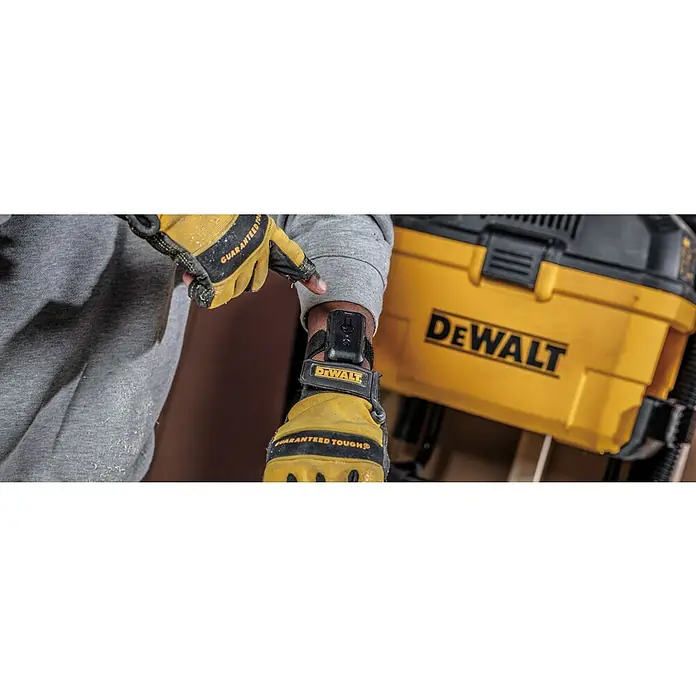 DeWalt Elektro-Nass- & Trockensauger DXV23G - 230 W, Behältervolumen: 23 l - Nahaufnahme eines Mannes mit DeWalt Handschuhen und einem DeWalt Gerät am Handgelenk, neben einem gelben DeWalt Werkzeug.