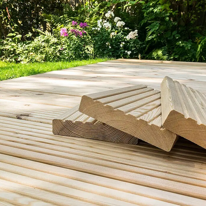 Home Deluxe Terrassenfliese ARIS Lärche 10 m² - Braun, Matt - Nahaufnahme von geriffelten Terrassendielen aus hellem Holz, die auf einer Holzterrasse im Garten liegen.