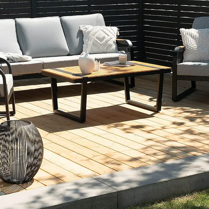 Home Deluxe Terrassenfliese ARIS Lärche 40 m² - Braun, Matt - Außenaufnahme eines modernen Couchtischs mit Holzplatte und schwarzem Metallgestell, der auf einer Holzterrasse vor Gartenmöbeln steht.