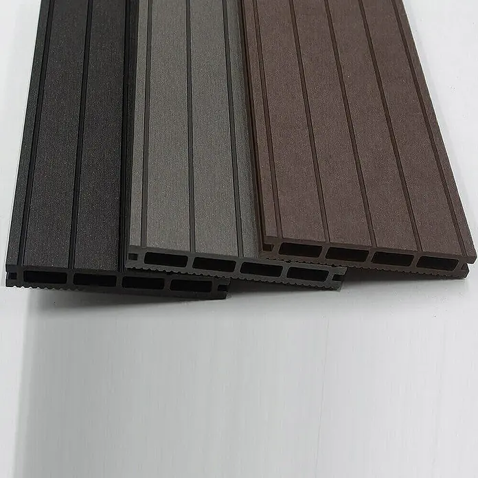 Home Deluxe Terrassenfliese SAMANA 50m² - Anthrazit, Matt - Nahaufnahme von drei Terrassendielen aus Verbundmaterial in Schwarz, Grau und Braun, die ihre Hohlkammerstruktur zeigen.