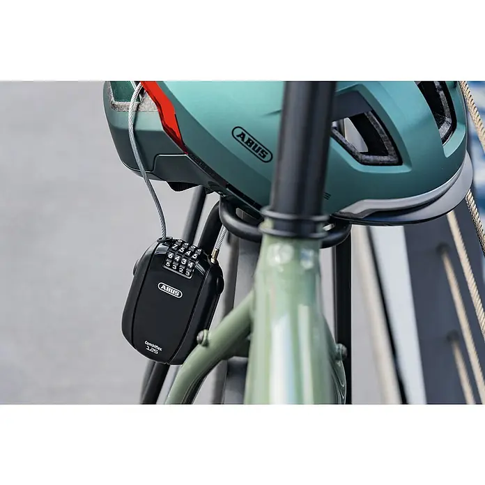 Abus Zahlen-Kabelschloss Combiflex Trip 125 - Länge: 125 cm, Passend für: Sicherung von Helmen u.Ä. - ABUS Fahrradhelm mit ABUS Combiflex 125 Kabelschloss zur Sicherung. Der Helm ist grün und das Schloss schwarz.