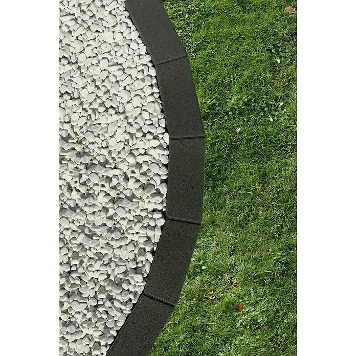Christoph Mähstein Trapez - 24 x 10 x 4,2 cm, Anthrazit, Beton - Nahaufnahme von Gartenbordüren, die einen Kiesweg von einem Rasen trennen. Die Bordüren sind aus dunklem Material gefertigt.