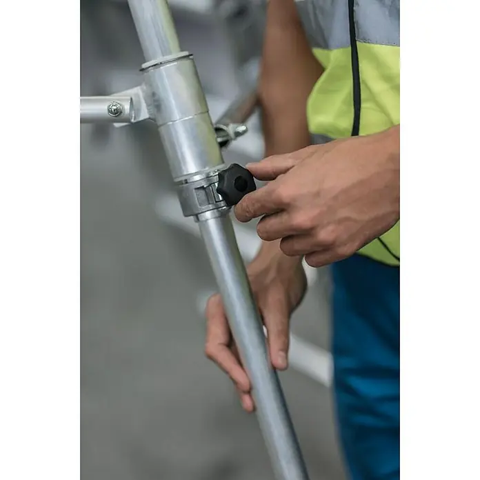 Proregal Stehleiter Plattformleiter Flexstep - Anzahl Tritte: 6 Stk., Belastbarkeit: 150 kg, Aluminium - Arbeiterhände stellen einen schwarzen Sterngriff an einem Aluminium-Gerüstbauteil ein.