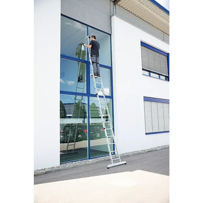 Proregal Anlegeleiter Glasreinigerleiter Unterteil mit nivello®-Traverse - Anzahl Tritte: 5 Stk., Belastbarkeit: 120 kg, Aluminium - Mann auf einer Aluminium-Mehrzweckleiter reinigt große Fenster eines Gebäudes.