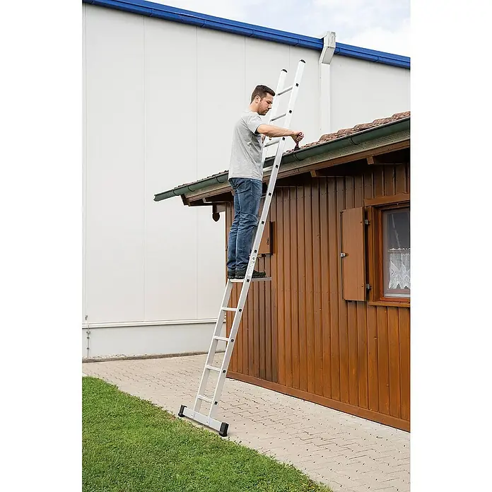 Proregal Anlegeleiter mit Standard-Traverse - Anzahl Tritte: 12 Stk., Arbeitshöhe: 4.600 mm, Belastbarkeit: 150 kg, Aluminium - Mann reinigt eine Dachrinne von einer silbernen Mehrzweckleiter mit Plattform.