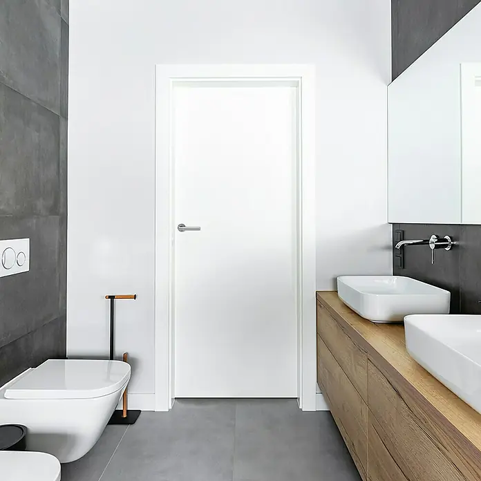 Diamond Doors Zimmertürgarnitur Moderna Smart2lock - Stärke Tür: 38 mm - 45 mm, Edelstahl, L-Form, Edelstahl matt, DIN Anschlag: Rechts, Passend für: Türen ohne Schlüssellochbohrung, Türen mit Schlüssellochbohrung benötigen zusätzlich eine Blindrosette - Modernes Badezimmer mit weißer Tür, grauen Fliesen und Holzelementen für einen stilvollen und minimalistischen Look.