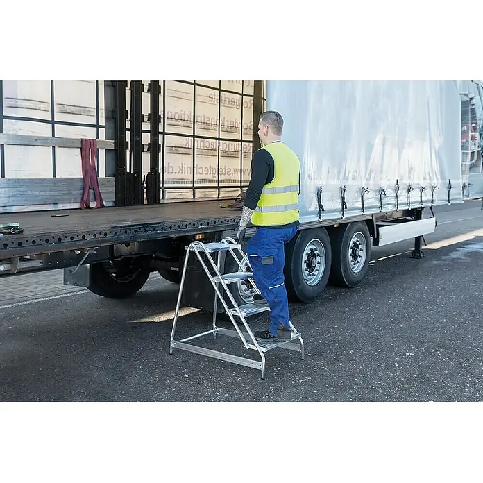 Proregal Treppenpodest Arbeitspodest einseitig begehbar - Anzahl Tritte: 3 Stk., Arbeitshöhe: 2.700 mm, Belastbarkeit: 150 kg, Aluminium - Silberne Aluminium-3-Stufen-Leiter wird zum sicheren Betreten eines LKW-Anhängers verwendet.