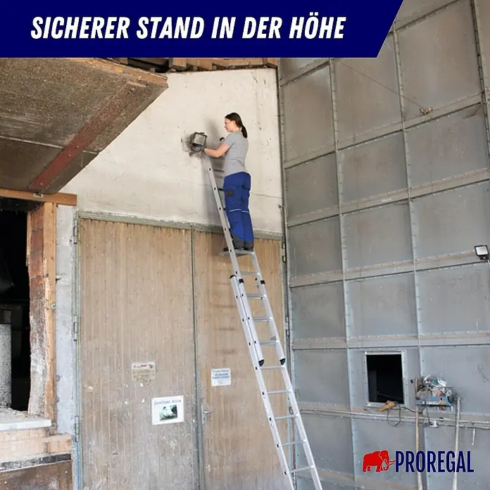 Proregal Schiebeleiter 2-teilig - Anzahl Tritte: 12 Stk., Arbeitshöhe: 4.100 mm, Belastbarkeit: 150 kg, Aluminium - Frau auf einer hohen, ausziehbaren Aluminiumleiter bei Arbeiten an einer Wand, sicherer Stand in der Höhe.