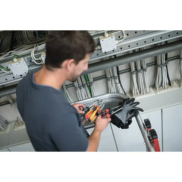 Proregal Stehleiter Plattformleiter klappbar und fahrbar - Anzahl Tritte: 5 Stk., Arbeitshöhe: 3.150 mm, Belastbarkeit: 150 kg, Aluminium - Techniker hält Zangen und Schraubendreher, trägt Arbeitshandschuhe, während er an einer Elektroinstallation arbeitet.