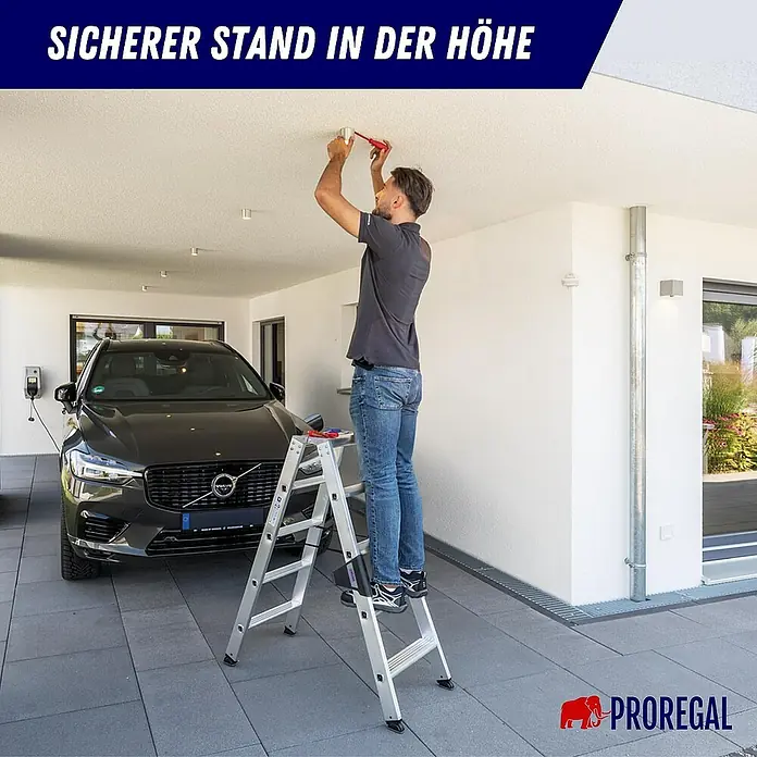 Proregal Doppel-Stehleiter beidseitig begehbar - Anzahl Tritte: 10 Stk., Arbeitshöhe: 2.650 mm, Belastbarkeit: 150 kg, Aluminium - Mann auf einer silbernen Aluminium-Klappleiter arbeitet an der Decke. Sicherer Stand in der Höhe.