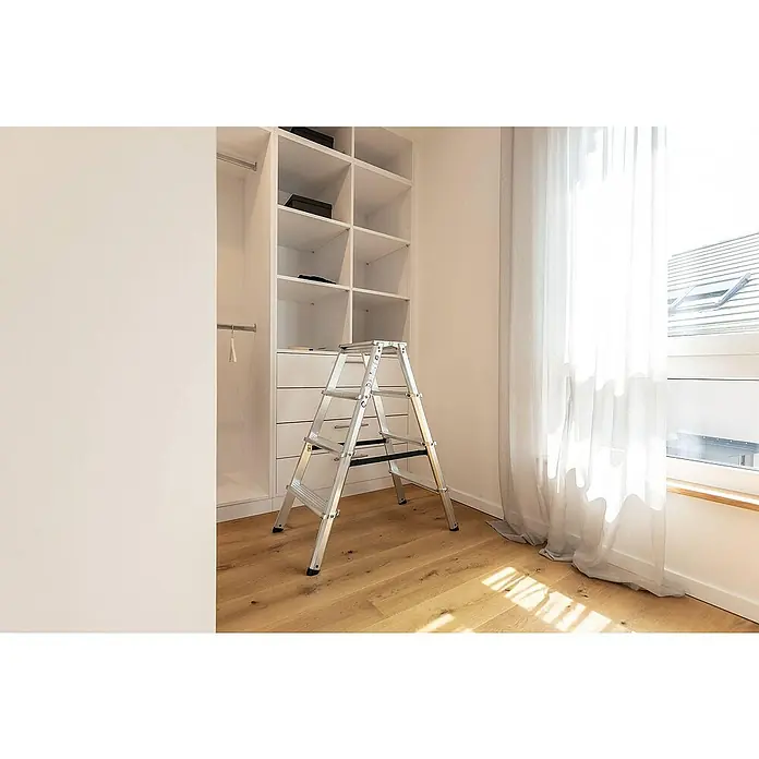 Proregal Doppel-Stehleiter beidseitig begehbar - Anzahl Tritte: 10 Stk., Arbeitshöhe: 2.700 mm, Belastbarkeit: 150 kg, Aluminium - Silberne Klappleiter mit schwarzen Akzenten auf Holzboden in einem Ankleidezimmer, einsatzbereit.