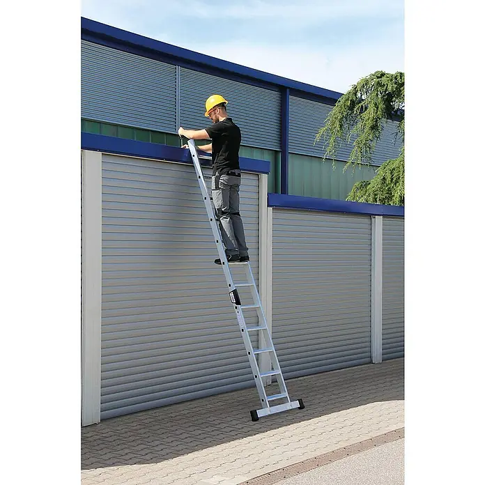 Proregal Anlegeleiter mit Standard-Traverse - Anzahl Tritte: 16 Stk., Arbeitshöhe: 5.300 mm, Belastbarkeit: 150 kg, Aluminium - Mann mit Schutzhelm auf silberner Aluminium-Ausziehleiter, der Arbeiten an einer Gebäudefassade durchführt.