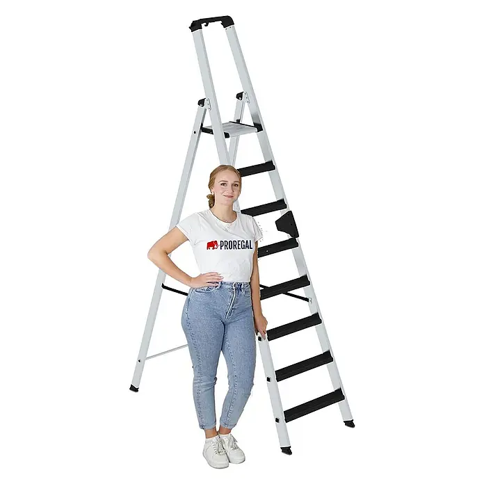 Proregal Stehleiter einseitig begehbar - Anzahl Tritte: 9 Stk., Arbeitshöhe: 4.100 mm, Belastbarkeit: 150 kg, Aluminium - Silberne/graue Stehleiter mit schwarzen Stufen, zusammen mit einer Frau zur Veranschaulichung ihrer Höhe und praktischen Nutzung.