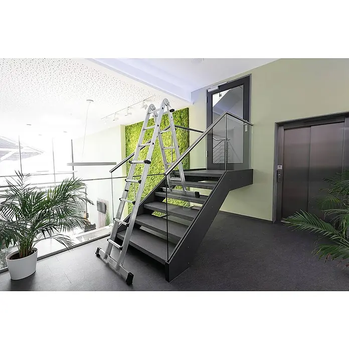 Proregal Teleskopleiter 4-teilig - Anzahl Tritte: 12 Stk., Arbeitshöhe: 4.200 mm, Belastbarkeit: 150 kg, Aluminium - Eine silberne Gelenkleiter steht auf einer modernen, dunklen Treppe mit Glasgeländer.