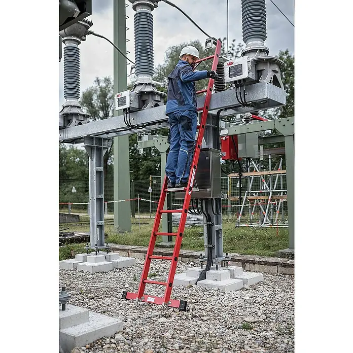 Proregal Anlegeleiter mit 14 Sprossen - Anzahl Tritte: 14 Stk., Arbeitshöhe: 5.300 mm, Belastbarkeit: 150 kg, Kunststoff - Rote Glasfaserleiter im Einsatz, ein Arbeiter wartet elektrische Anlagen in einer Umspannstation.