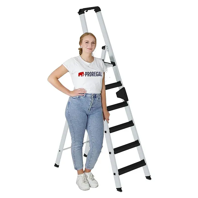 Proregal Stehleiter einseitig begehbar - Anzahl Tritte: 6 Stk., Arbeitshöhe: 3.400 mm, Belastbarkeit: 150 kg, Aluminium - Eine Frau steht neben einer silbernen und schwarzen Klappleiter mit fünf Stufen.