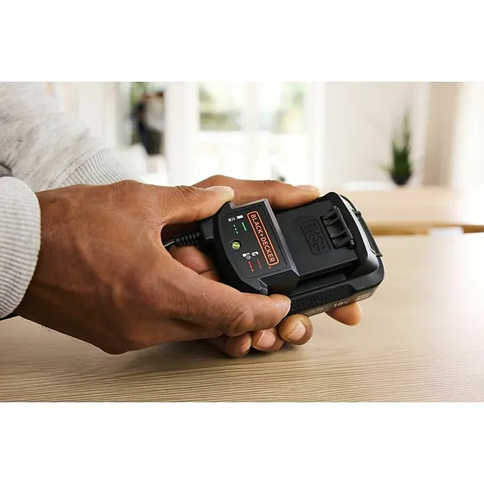 Black+Decker 18V PowerConnect Batería y cargador - 18 V, 2 Ah, Iones de litio - Una persona sostiene un cargador de batería de iones de litio Black+Decker en sus manos, con los indicadores de carga claramente visibles.