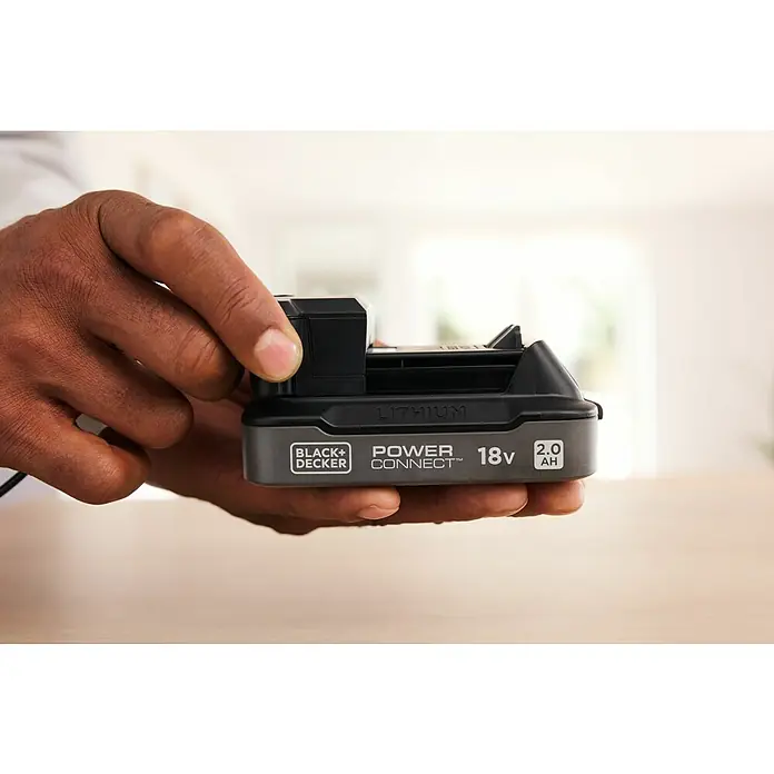 Black+Decker 18V PowerConnect Batería y cargador - 18 V, 2 Ah, Iones de litio - Una batería Black+Decker Power Connect de 18V se sostiene en una mano. La batería de iones de litio tiene 2.0 Ah.
