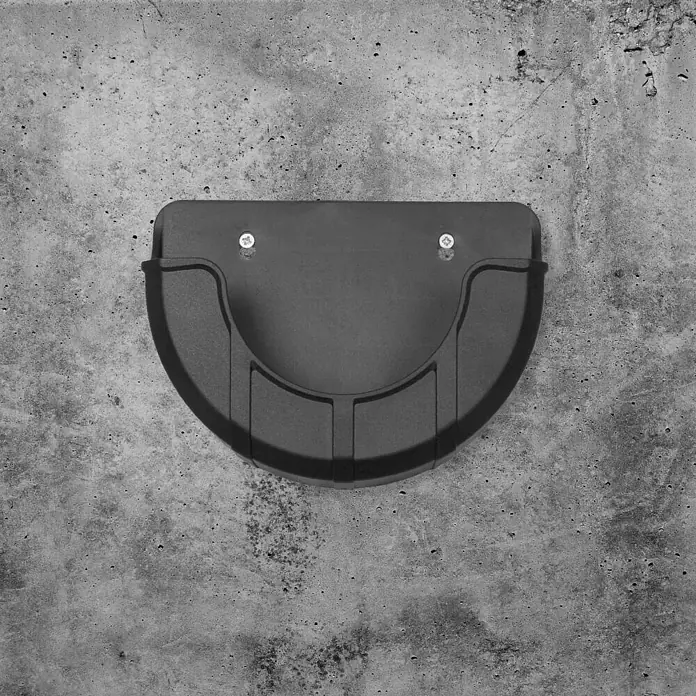 Batavia Maxxpack Wandhalterung - Kunststoff, Passend für: Batavia Akku-Reinigungsbürste Twin Brush - Halbkreisförmige, schwarze Halterung an einer grauen Betonwand befestigt, die ein minimalistisches und funktionales Design aufweist.