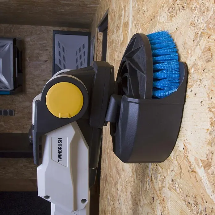 Batavia Maxxpack Wandhalterung - Kunststoff, Passend für: Batavia Akku-Reinigungsbürste Twin Brush - Das Bild zeigt eine an der Wand montierte TWINBRUSH-Reinigungsbürste mit blauem Bürstenkopf, die für Reinigungsarbeiten im Außenbereich verwendet wird.
