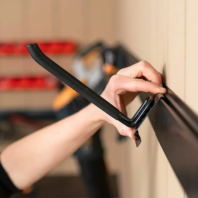 Batavia Maxxclick Systemhalter Click & Go Rail - Länge: 58 cm - Eine Hand befestigt einen schwarzen Haken an einer schwarzen Schiene. Der Haken hat einen gepolsterten Griff für zusätzlichen Komfort.