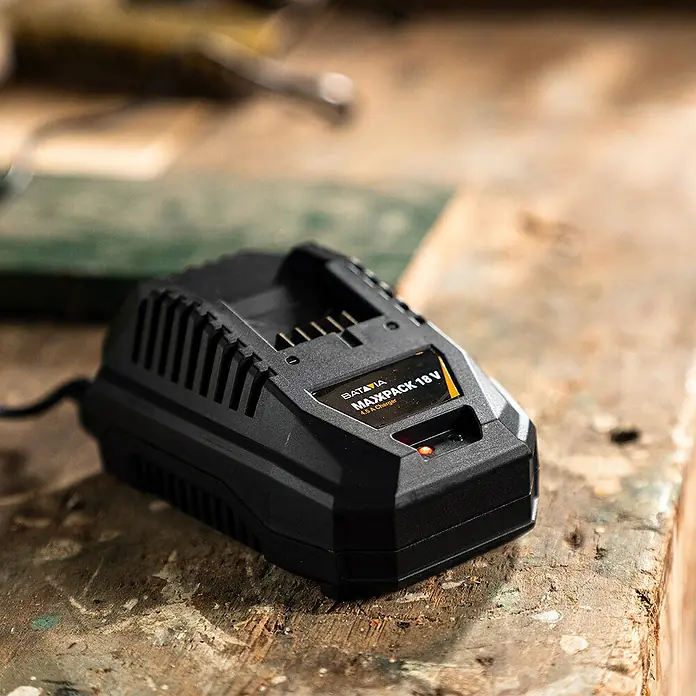 Batavia Maxxpack Akku-Schnellladegerät - Passend für: Batavia Akkus der Maxxpack-Kollektion - Nahaufnahme eines schwarzen Batavia MAXXPACK 18V 4.5A Ladegeräts auf einer Werkbank, das eine rote LED-Anzeige zeigt.