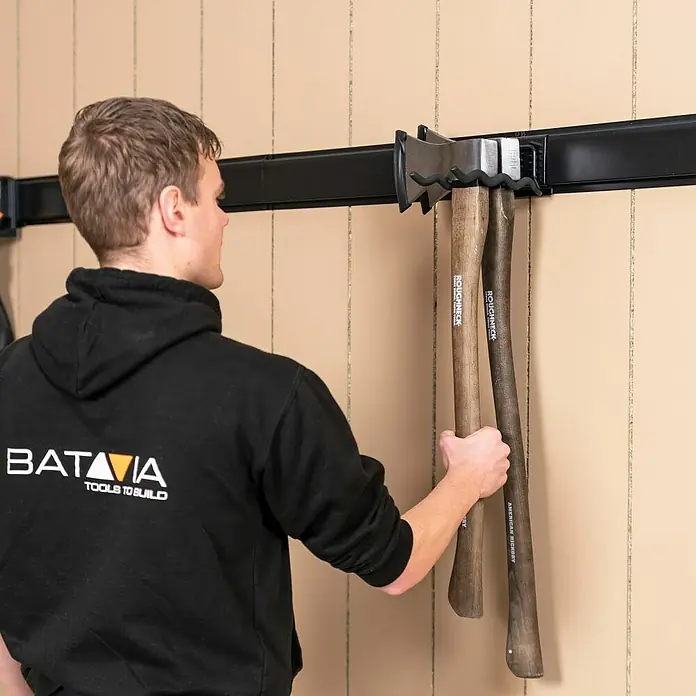 Batavia Maxxclick Doppel-Wandhaken Wave - Passend für: Batavia Maxxclick Wellenhaken - Ein Mann hängt Äxte mit dem Roughneck Axt-Aufbewahrungssystem an eine Wand. Praktische Werkzeugaufbewahrung für Garage oder Werkstatt.