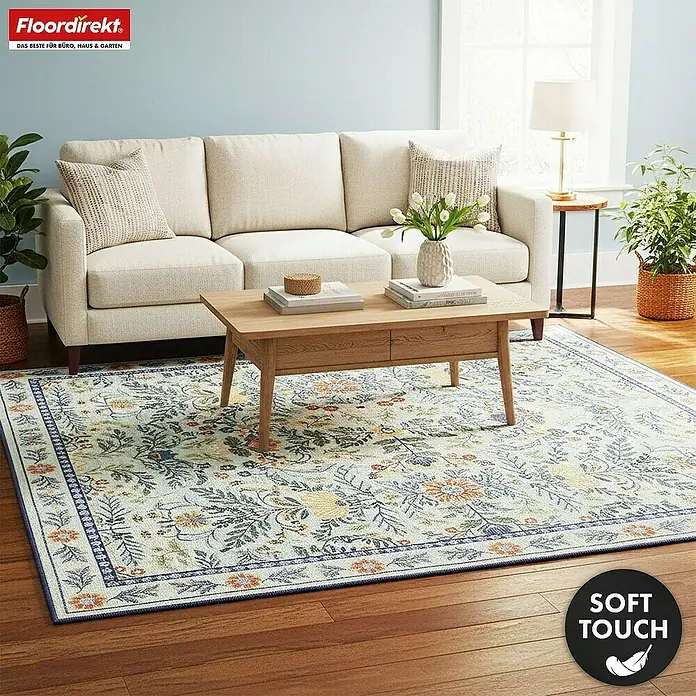 Floordirekt Kurzflorteppich Cascada 160 x 230 cm - Hellgrün - Hellfarbiger Teppich mit floralem Muster in Blau, Orange und Gelb und blauem Rand, unter einem Holztisch in einem Wohnzimmer.