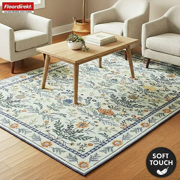 Floordirekt Kurzflorteppich Cascada 160 x 230 cm - Hellgrün - Ein heller Teppich mit leuchtendem Blumenmuster in Blau, Orange und Grün, mit markanter Bordüre, unter einem Holztisch im Wohnzimmer.