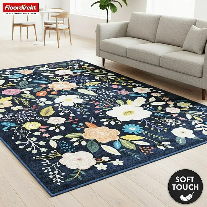 Floordirekt Kurzflorteppich Damaskus 160 x 230 cm - Blau - Ein dunkelblauer Teppich mit farbenfrohem Blumenmuster, mit großen weißen, rosa und gelben Blüten, auf hellem Holzboden im Wohnzimmer.