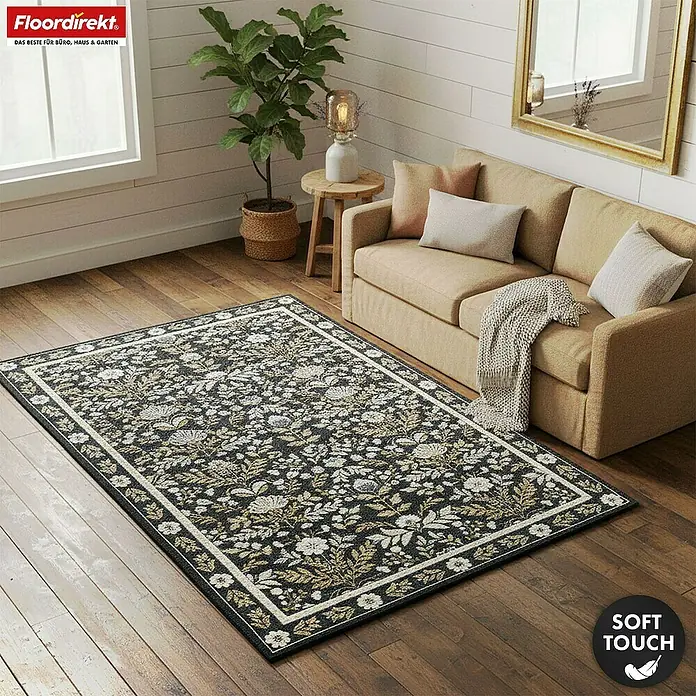 Floordirekt Kurzflorteppich Aristo 160 x 230 cm - Schwarz, 230 x 160 cm - Ein dunkelgrauer Teppich mit weißen und goldenen Blumenmustern und hellem Rand, auf Holzboden unter einem Sofa im Wohnzimmer.