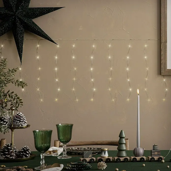 ECD Germany LED-Lichtervorhang 240 LEDs 6m für Innen & Außen IP44 Warmweiß - Innen, Warmweiß, 240 Stk., Netzbetrieben - Warmweiße LED-Lichterkette vertikal an einer Wand drapiert, die einen festlichen Vorhang-Effekt erzeugt.