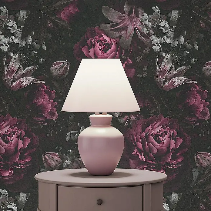 Tadessi Vliestapete M1-No.3456 - Schwarz, Floral, 10,05 x 0,53 m - Rosafarbene Tischlampe mit weißem Schirm auf passendem Beistelltisch vor dunkler floraler Tapete.