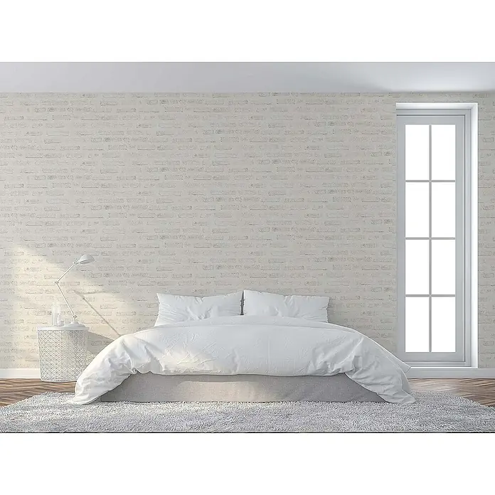 Tadessi Vliestapete M1-No.418 - Grau, Steinoptik, 10,05 x 0,53 m - Minimalistisches Schlafzimmer mit großem weißem Bett, Beistelltisch mit Lampe, weißer Ziegelwand und hohem Fenster, das eine helle, ruhige Einrichtung zeigt.