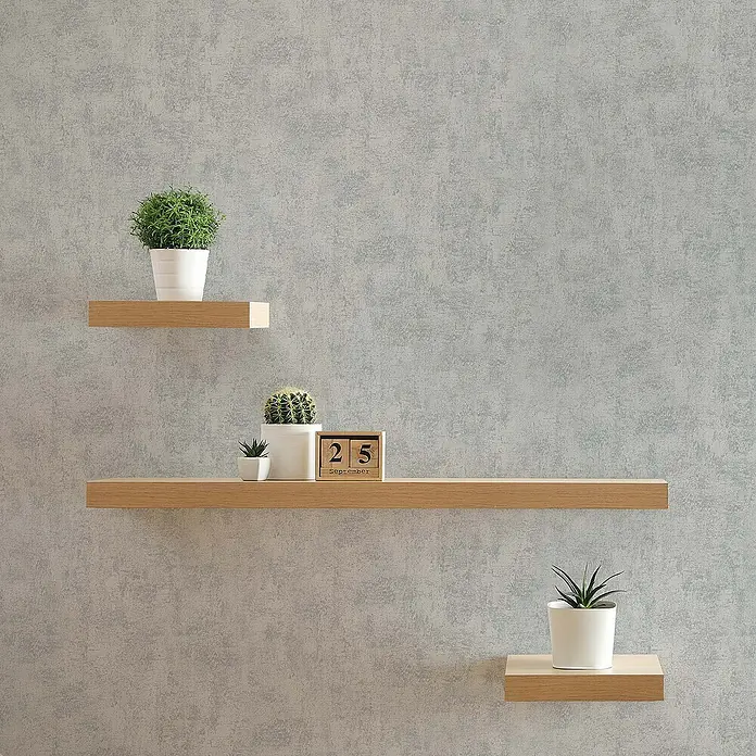 Tadessi Vliestapete M1-No.16 - Grau, Steinoptik, 10,05 x 0,53 m - Drei schwebende Regale aus hellem Holz mit Pflanzen und einem Kalender an einer strukturierten Wand.