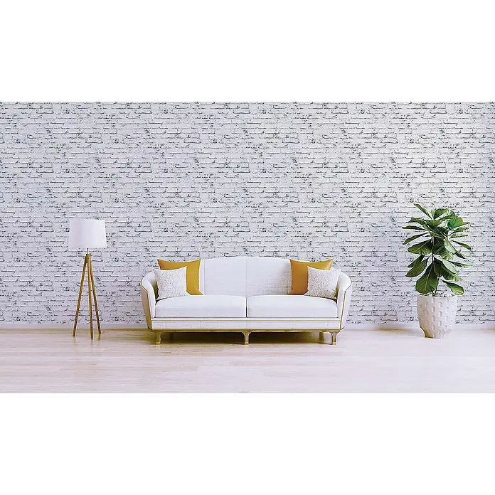 Tadessi Vliestapete M1-No.869 - Grau, Steinoptik, 10,05 x 0,53 m - Ein gemütliches Wohnzimmer mit weißem Sofa, senffarbenen und weißen Kissen, einer Holzstehlampe und einer großen Topfpflanze vor einer weißen Ziegelwand.