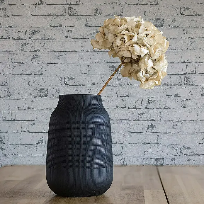 Tadessi Vliestapete M1-No.869 - Grau, Steinoptik, 10,05 x 0,53 m - Mattschwarze, strukturierte Vase mit weitem Hals, mit getrockneten Hortensien auf einer Holzfläche.