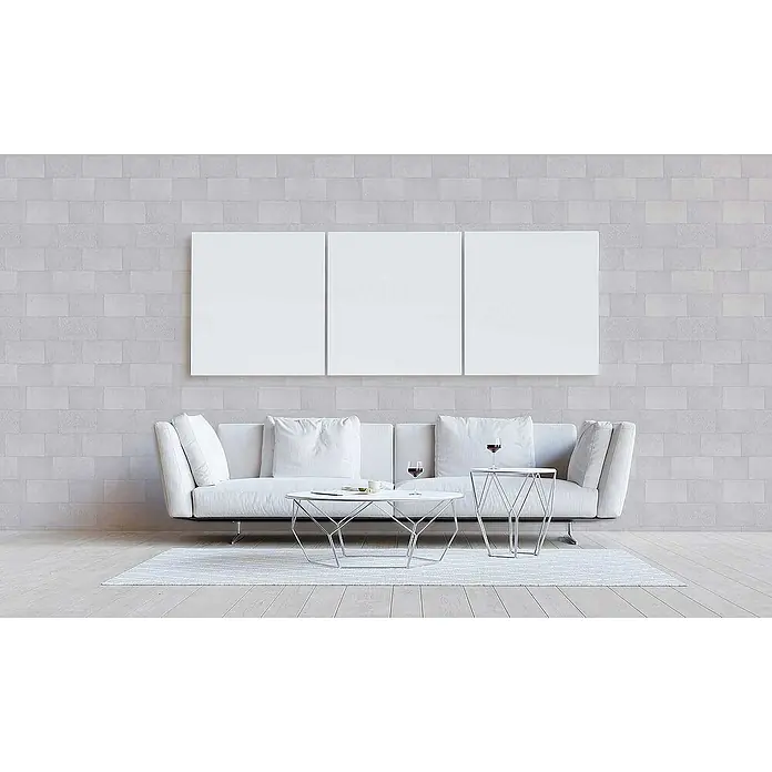 Tadessi Vliestapete M1-No.3391 - Grau, Steinoptik, 10,05 x 0,53 m - Drei leere weiße Leinwände hängen über einem modernen weißen Sofa mit eleganten Metall-Couchtischen in einem zeitgenössischen Wohnzimmer.