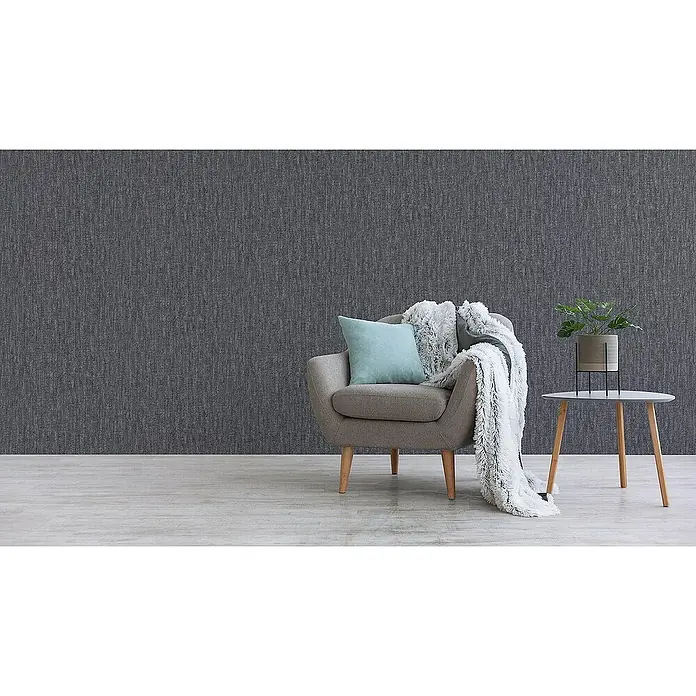 Tadessi Vliestapete M1-No.3403 - Grau, Sonstiges, 10,05 x 0,53 m - Dunkelgraue Tapete mit subtiler vertikaler Textur in einem stilvollen Raum mit Sessel und Pflanze.