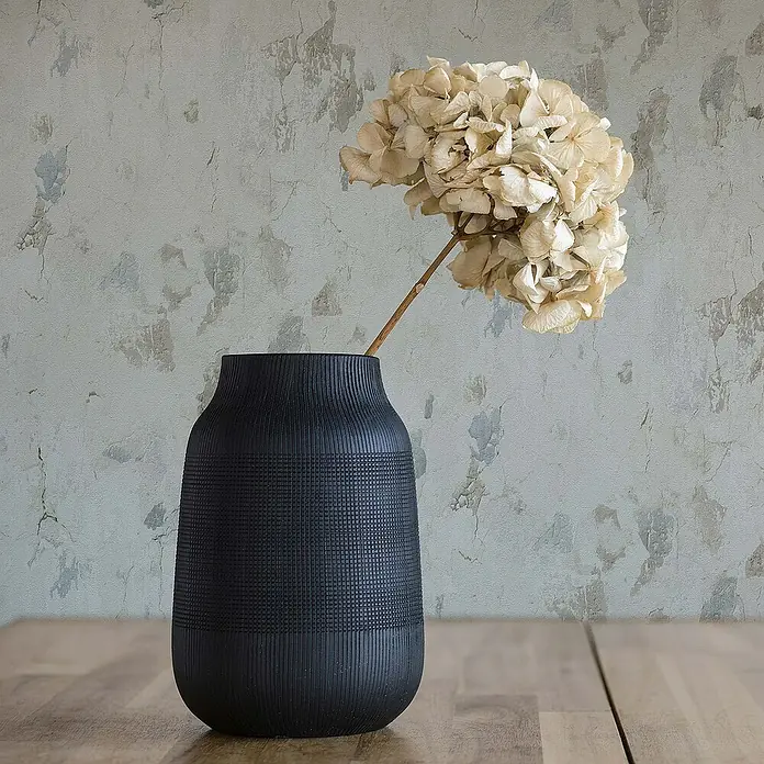 Tadessi Vliestapete M1-No.649 - Grau, Steinoptik, 10,05 x 0,53 m - Schwarze strukturierte Vase mit getrockneten Hortensien auf einem Holztisch.