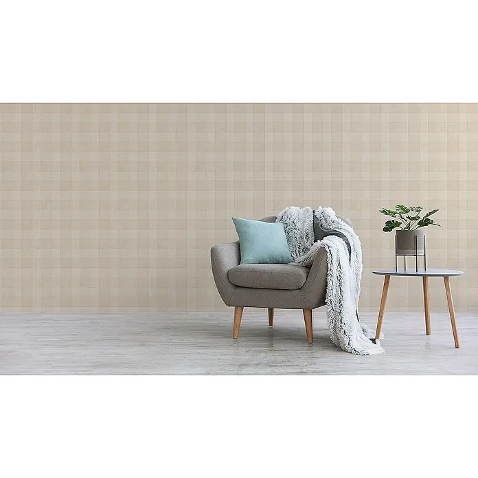 Tadessi Vliestapete M1-No.3531 - Beige, Streifen, 10,05 x 0,53 m - Gemütliche Wohnecke mit grauem Sessel, blauem Kissen und flauschiger Decke. Ein Beistelltisch mit Pflanze steht vor einer hell gemusterten Wand.