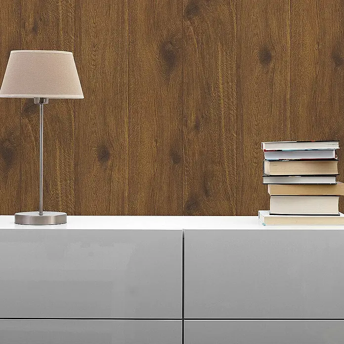 Tadessi Vliestapete M1-No.23 - Beige, Holzoptik, 10,05 x 0,53 m - Dunkelbraune Holzwandverkleidung mit sichtbarer Maserung, als stilvolle Akzentwand über einem modernen grauen Schrank mit Lampe und Büchern.